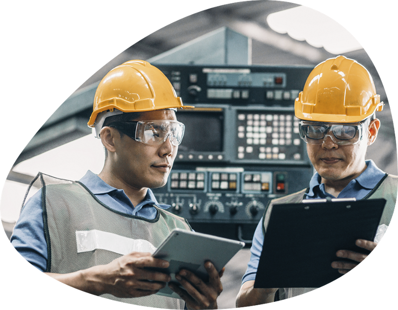 Two engineers with hard hats and safety goggles examining papers papers